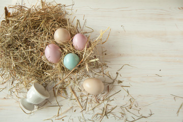 Fototapeta na wymiar Stack of colorful easter eggs on straw with wooden table background