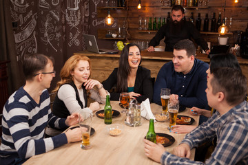 Group of young friends sitting around table in bar togethe