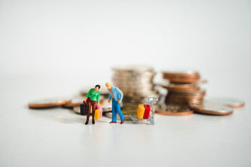 Miniature people, man and woman carry bags on pile coins background using as job retirement and travel concept