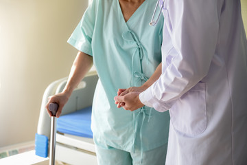 The doctor shook hands, encouraged and supported the patient, Which holds a cane to help support in...