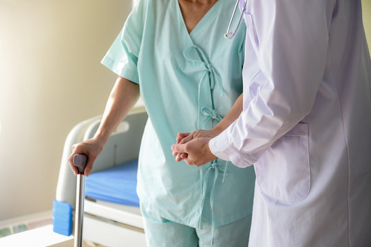 The doctor shook hands, encouraged and supported the patient, Which holds a cane to help support in the hospital, to healthy and health insurance concept.