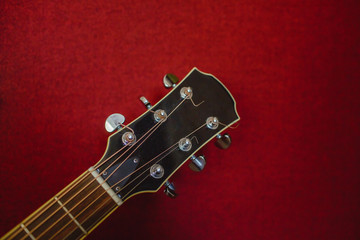 Close-up of guitar over red textured background.
