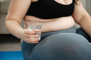 Plakat sport, fitness, yoga class, relaxation, balance, flexibility. overweight woman taking a break, drinking water between sets during home yoga workout
