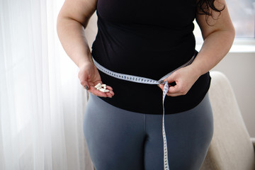 weight loss, medical therapy, diabetes prevention. Fat obese woman with pills and measure tape