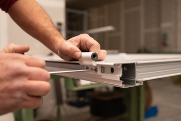 close up of worker hands assembling a hinge on aluminium door - obrazy, fototapety, plakaty