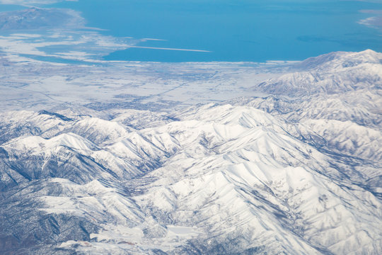 Looking Out Of An Airplane Window At The Great Salt Lake In Utah, And Snow Covered Mountains