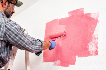 Professional house painter at work painting the wall © francescomou
