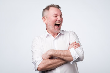 Obraz premium Smiling elderly man in white shirt standing at studio.