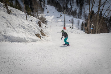 Adult woman riding on a snowboard with big speed with cable lift in the background