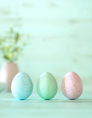 Three colorful Easter eggs on mint cyan wood