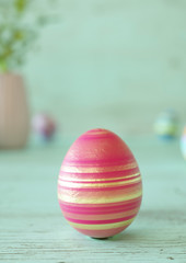 One Easter egg decorated on mint green wood table