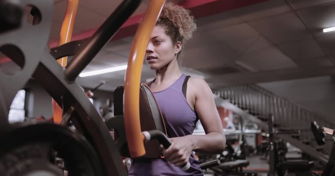 Strong woman working out on weight machine at the gym