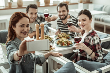 Positive delighted brunette girl taking photo on her gadget