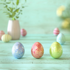 Three colorful Easter eggs on green wood