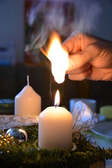 Kerze auf einem Adventskranz mit einem Streichholz entzünden Hand