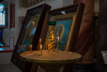 Candles in Russian orthodox cathedral with icons on background
