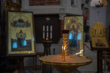 Candles in Russian orthodox cathedral with icons on background