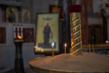 Candles in Russian orthodox cathedral with icons on background