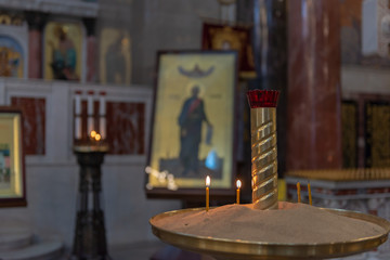 Candles in Russian orthodox cathedral with icons on background
