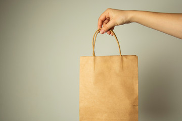 Closeup of female hand holding craft paper package., design mock up. Zero easte concept.