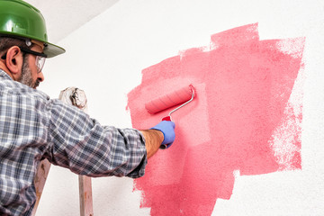 Professional house painter at work painting the wall © francescomou