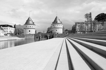 Monochrome cityscape with ancient Broel Towers, a classified monument and a landmark in the Belgian city of Kortrijk alongside the Leie river.