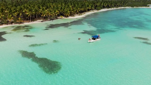 Aerial Descent: Motorboats Floating on Blue Water in front of Tropical Beach