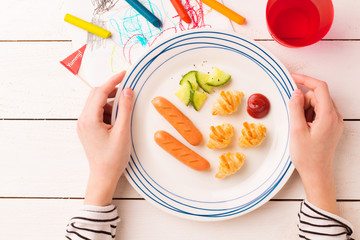 Breakfast in child's hands - weenies, mini croissants and cucumber