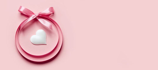 Valentine's Day greeting card. A circle of satin ribbons with a bow, inside of which is a heart on a bright background.