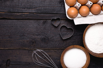 Kitchen tools, flour and sugar on a wooden background