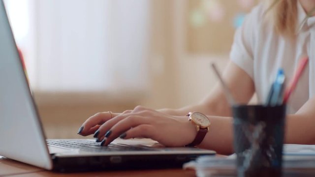 Girl in a white blouse close up typing on the laptop keyboard, on hand clock and manicure