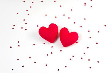 Red heart shaped fabric and red heart glitter on white background