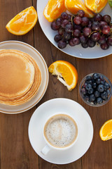 Top view of healthy breakfast. Deliciouse homemade american pancakes with cup of coffee and fruits. Wooden table, beautiful morning in garden.