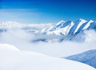 Junger sportlicher Mann fährt Ski, macht Winter Sport in einem Winter Paradis. Schnee bedeckte Berge, blauer Himmel und Farbenfroher Ski Anzug