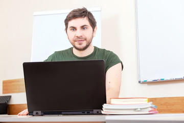 Portrait teacher man mail classroom blue eyes laptop notebook computer online internet young training school t-shirt informal