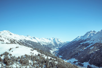 Young sporty man is skiing, doing winter sports in a winter paradise. Snow covered mountains, blue sky and colorful ski suit