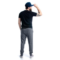 Man in black t-shirt with cap looks on white background isolation, back view