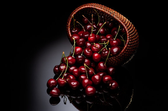 Fresh cherry in a wicker basket on a black background.