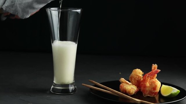 Fried Shrimps tempura with lime in black plate and pouring beer in glass on pink or peach concrete surface background. Copy space Seafood tempura dish served japanese or eastern Asia style
