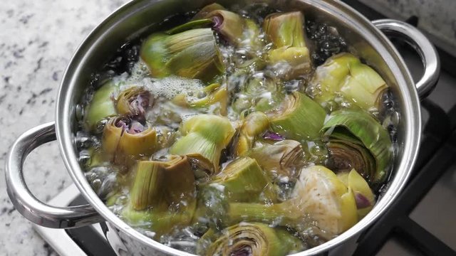 Boiling and cooking artichokes in saucepan, closeup