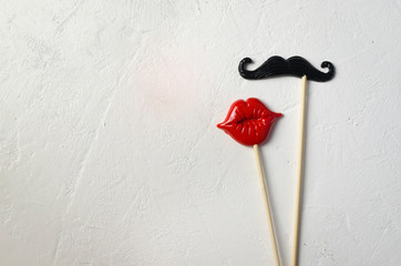 Photo booth props mustache lips on white stone board background.