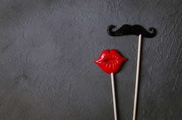 Photo booth props mustache lips on dark stone board background.