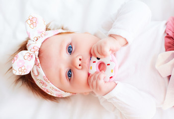 cute little baby girl nibble a silicone doughnut teether