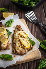 Baked pollock fillet with lemon and spinach on a wooden background