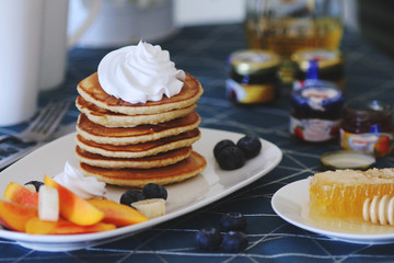 Breakfast pancakes served with honey and fruits