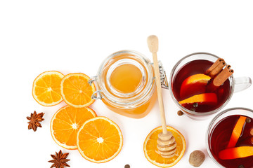 Hot red mulled wine, bee honey, slices of oranges and spices isolated on white background. Free space for text.