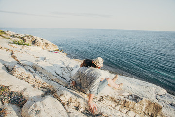 man sitting on a rock and looking at the sea