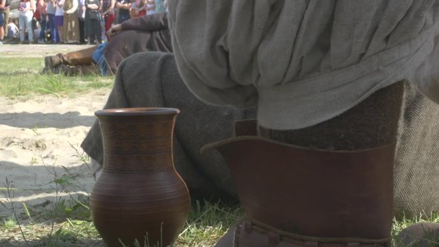 Antique reconstruction, Men in ancient costumes sit on the field, rest on the sand crock