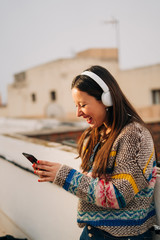 Young woman listening to music via headphones on rooftop