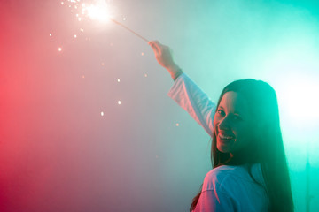 Pretty smiling young woman holding big and colorful sparkler